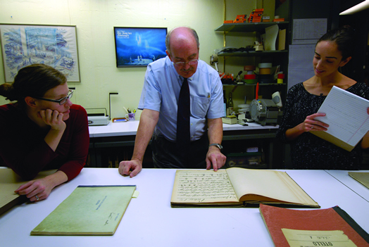 Melissa Robason, Robert Sutherland and Sarah Vonsattel study a historic violin part of Wagner's "Rienzi."