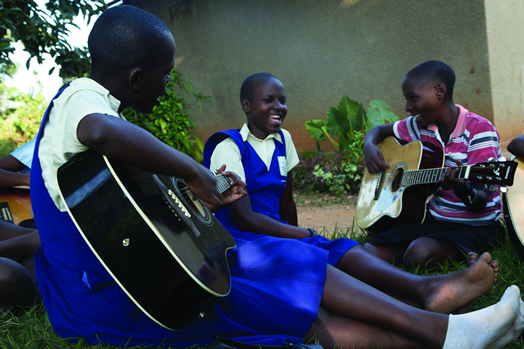 SMILES AND STRUMMING: Ugandan children experience the joy of playing music.